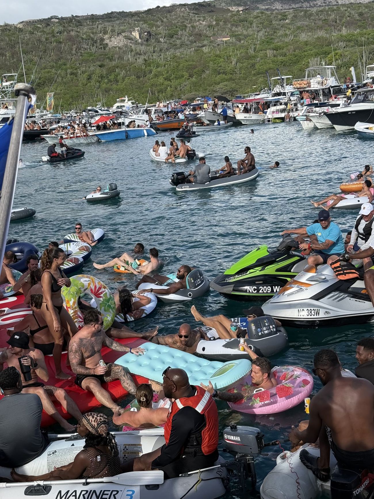 Crowds on floats and jet skis between rafted boats at Fuik Bay on a Sunday
