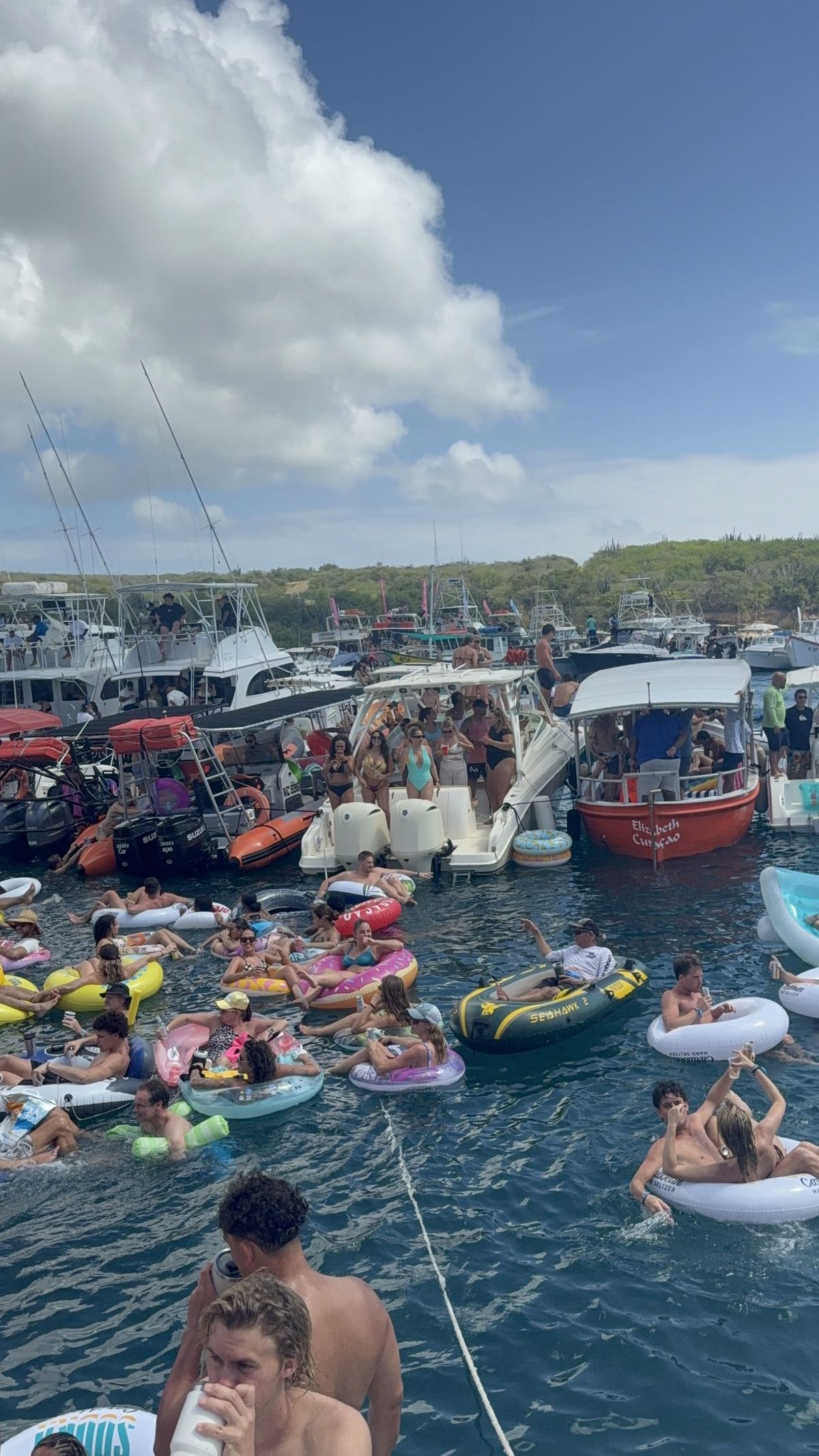 Swimmers on inflatable rings beside rafted boats at Fuik Bay