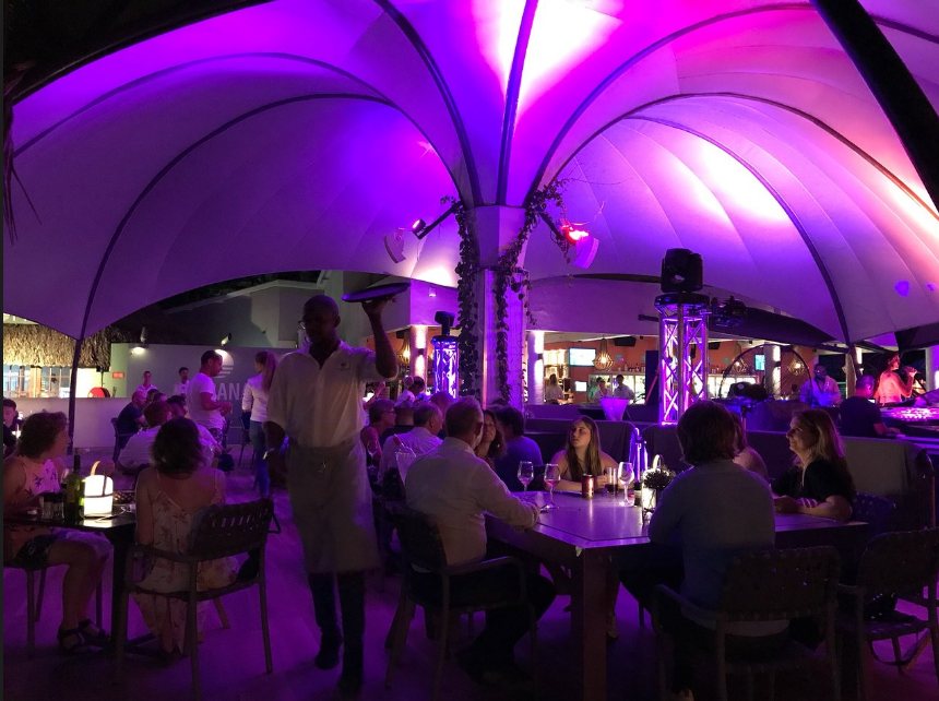 Beach club dining under lit canopies at night, Curaçao